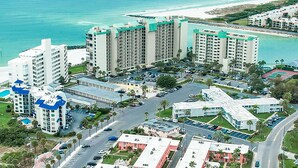 A coastal hotel complex with multiple high-rise buildings, a parking area, and a beach in the background.