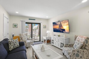 Un salon comprenant un canapé, des fauteuils, une table basse, un téléviseur et un balcon avec vue.