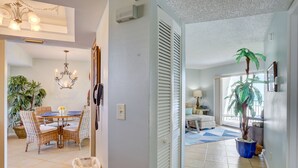 A spacious living area with a dining table, wicker chairs, a chandelier, and a potted plant. - 🌅 Caprice Resort Unit #303 – Gulf Front Escape for Up to Four Guests (St Pete Beach)