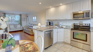 A modern kitchen with white cabinetry, a stainless steel oven, and a built-in microwave.
