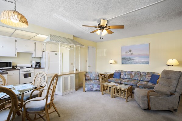 A compact living space with a kitchenette, a dining area, a sofa, and a chair. - 💸 Ground-Floor 1BR Condo — Simple Comfort & Great Value at Gulf Winds (ST PETE BEACH)