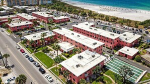 A coastal hotel with multiple red buildings, a beach, and a clear view of the ocean.