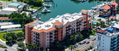 A multi-story hotel with balconies, located near a marina with boats.