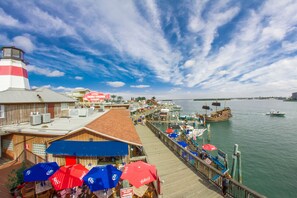 A waterfront pier with a lighthouse, boats, and a restaurant with outdoor seating.