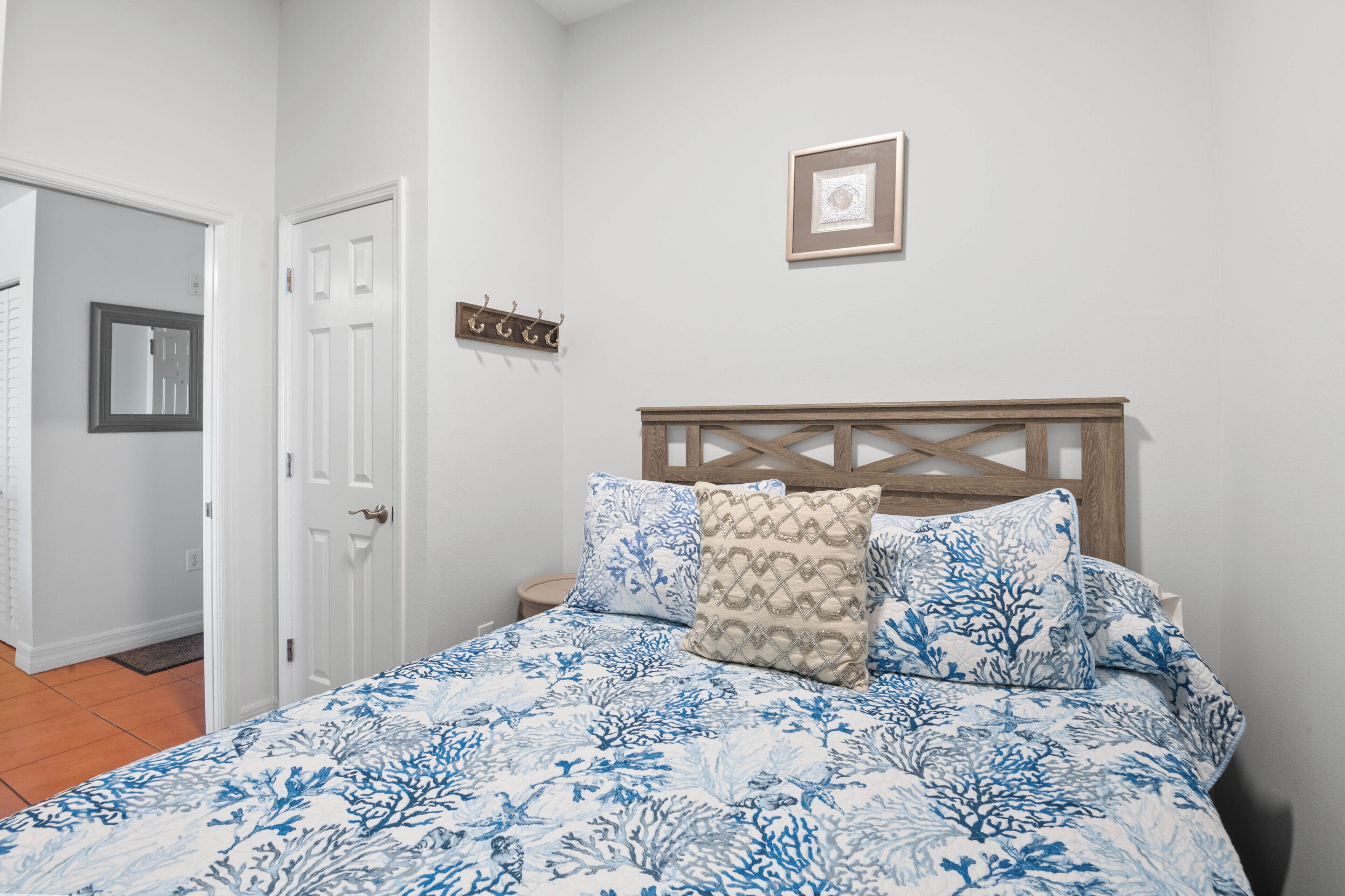 A bedroom with a bed, a wooden headboard, a wall-mounted picture, and a door.
