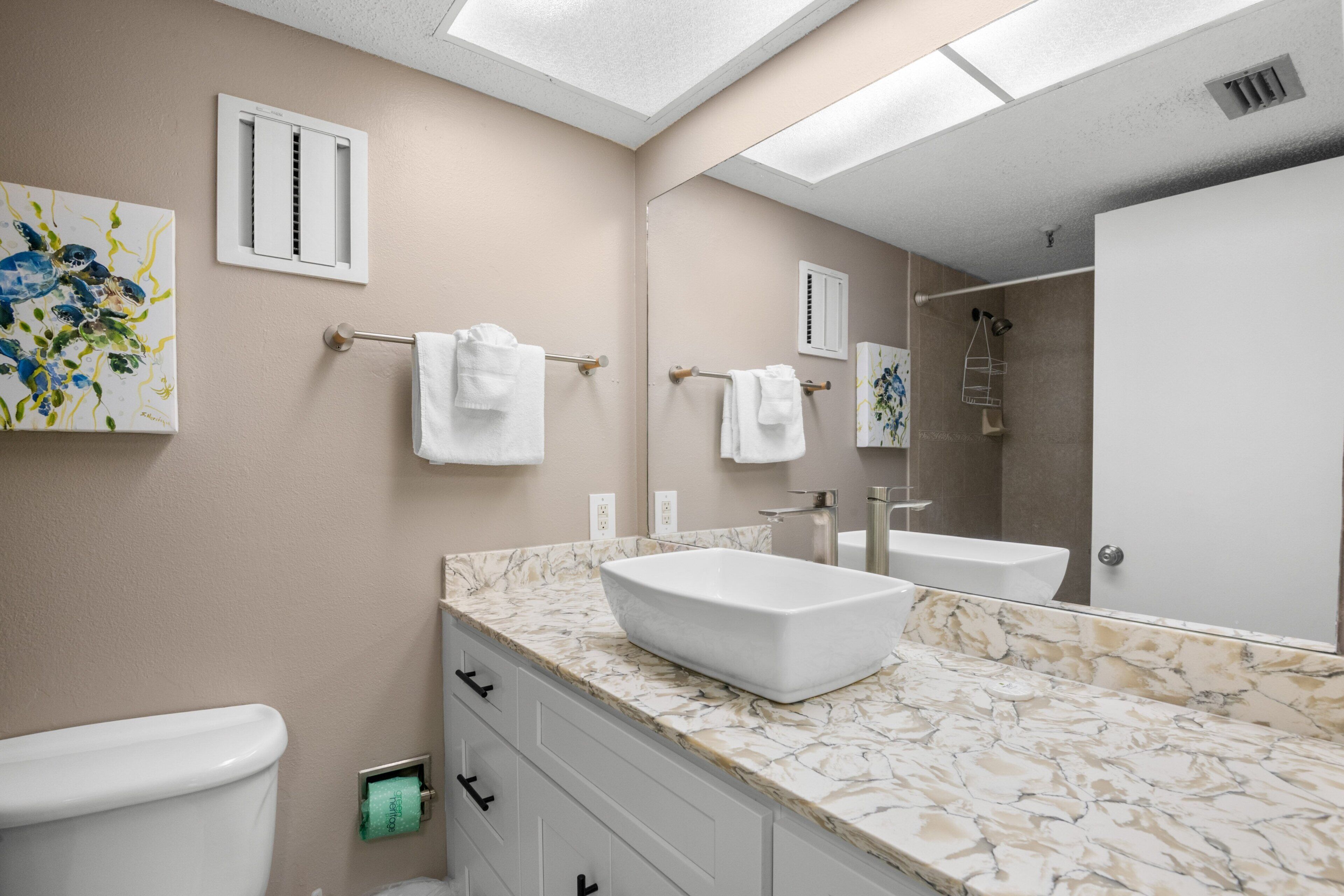 Ein modernes Badezimmer mit großem Spiegel, weißem Waschbecken und Toilette.