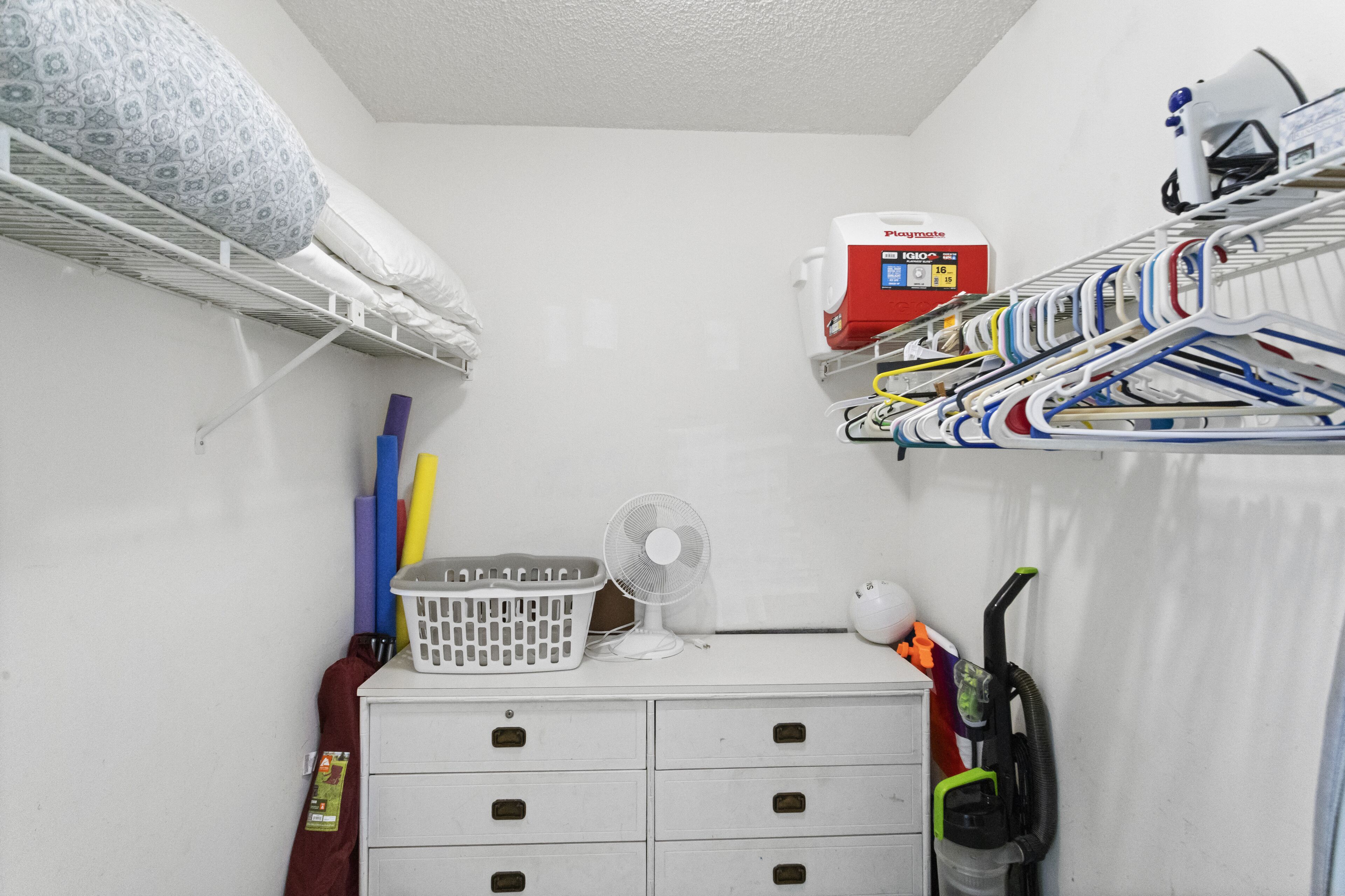 A compact room with a bunk bed, a laundry basket, a fan, and a vacuum cleaner.