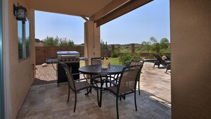 Patio esterno con barbecue, tavolo e sedie da pranzo.