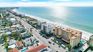 A coastal hotel with a beach view, multiple floors, and a swimming pool.