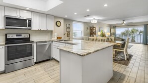 A modern kitchen with a central island, built-in appliances, and a dining area with a view.