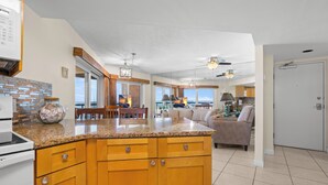 A modern kitchen with granite countertops, wooden cabinets, and a dining area with a table and chairs.