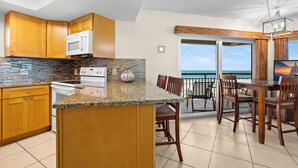 A kitchen with wooden cabinets, a granite countertop, and a view to the outside.