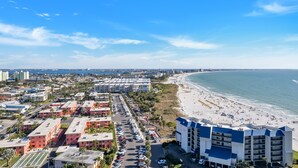 A coastal cityscape with a beachfront hotel, parking lots, and residential buildings.
