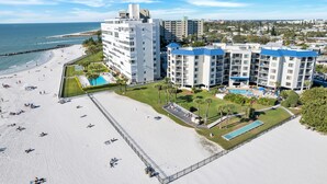 A beachfront hotel with multiple buildings, a sandy beach, and a swimming pool.