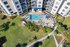Oversigtsbillede af et hotel med en central swimmingpool omgivet af liggestole og et lille dæk.