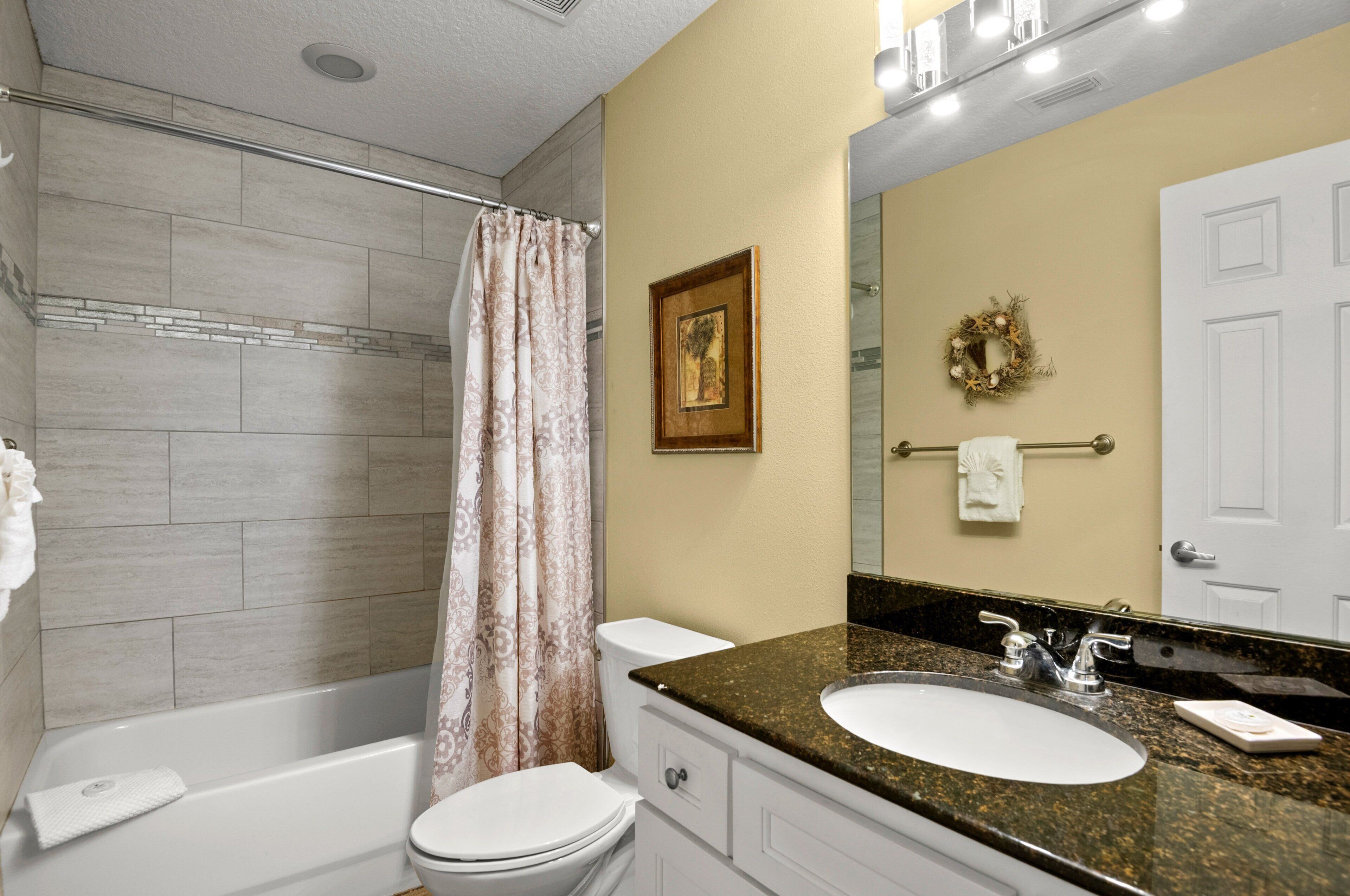 A bathroom with a bathtub, toilet, sink, and a mirror.