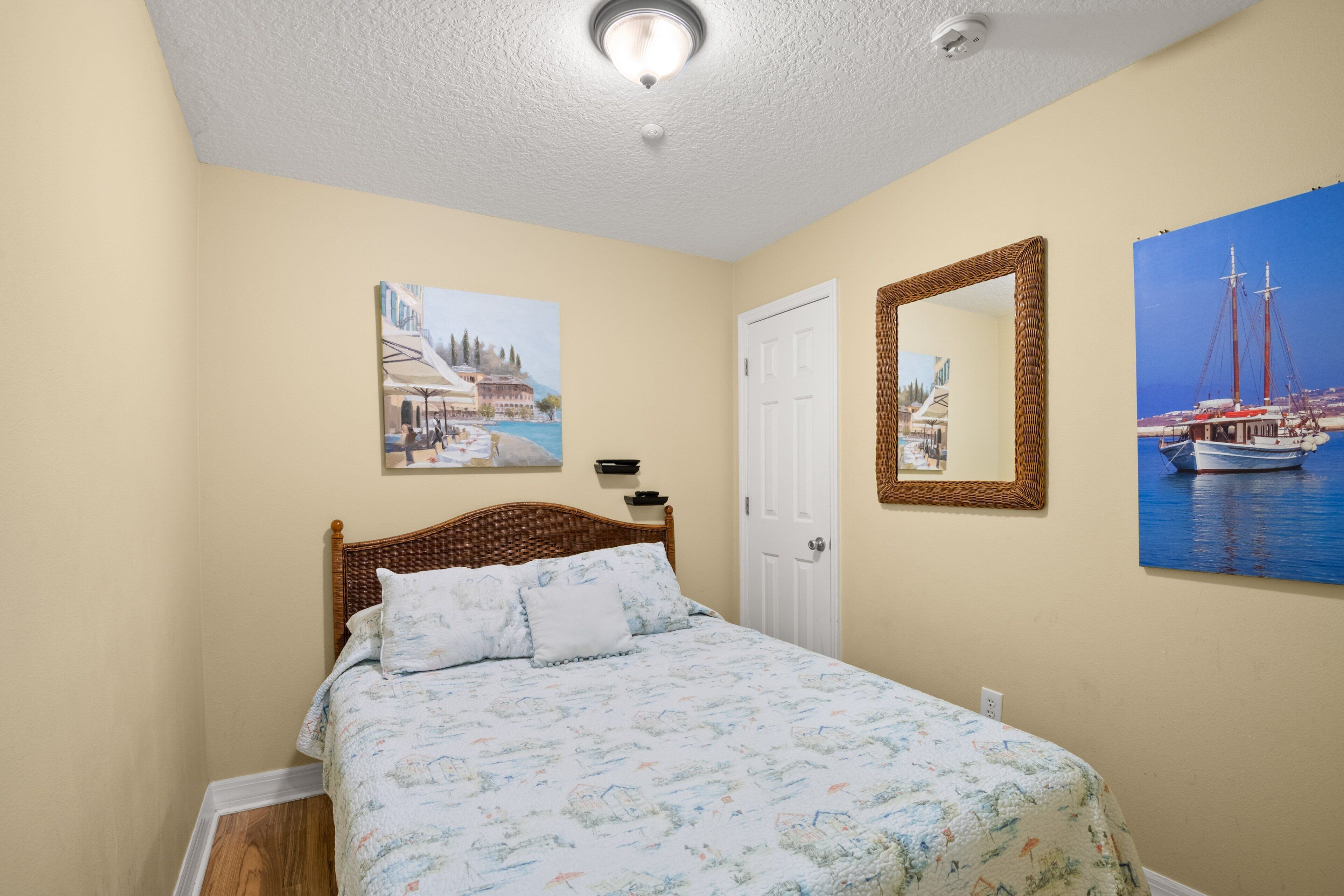A bedroom with a bed, a door, and two wall-mounted pictures.