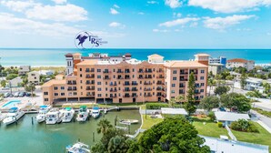 A resort with multiple buildings, a marina with boats, and a clear view of the ocean.