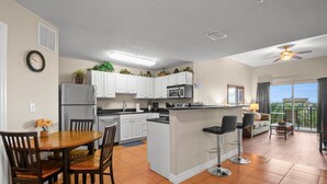 A modern kitchen with white cabinets, a stainless steel refrigerator, and a central island with bar stools.
