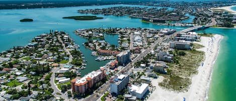 An aerial view of a coastal city with a marina, beachfront, and dense residential areas.