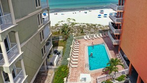 A hotel with a pool, beach view, and multiple balconies.