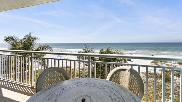 A balcony with a view of the beach and ocean.