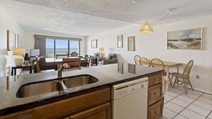 A spacious kitchen with a large island, a dishwasher, and a dining area with chairs and a table.