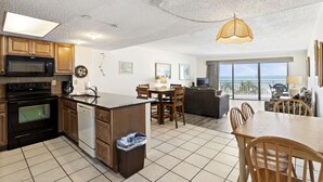 A spacious kitchen with modern appliances, a dining area with wooden furniture, and a balcony with a view.