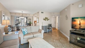 A spacious living area with a sofa, coffee table, and a TV on a wooden cabinet.