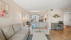 A living room with a sofa, coffee table, and a dining area with a table and chairs.