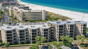 A beachfront hotel with multiple balconies, a parking lot, and a view of the beach and ocean. - 🌴 Gulf View Condo — Gulf Strand Resort, St. Pete Beach (St Pete Beach)