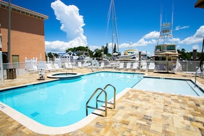 A swimming pool with a lifeguard stand, lounge chairs, and a view of boats in the background.