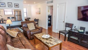 A living room with a leather sofa, a coffee table, and a television.