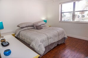 Une chambre à coucher avec un lit, des tables de chevet, une lampe et une fenêtre.