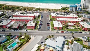 Un hotel frente al mar con varias construcciones de techo rojo, un estacionamiento y vistas a la playa.