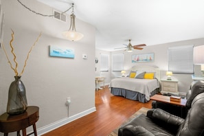 A bedroom with a bed, bedside tables, a ceiling fan, and a window with blinds.