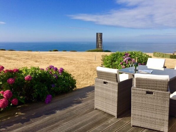 An outdoor seating area with wicker furniture and a view of the sea.