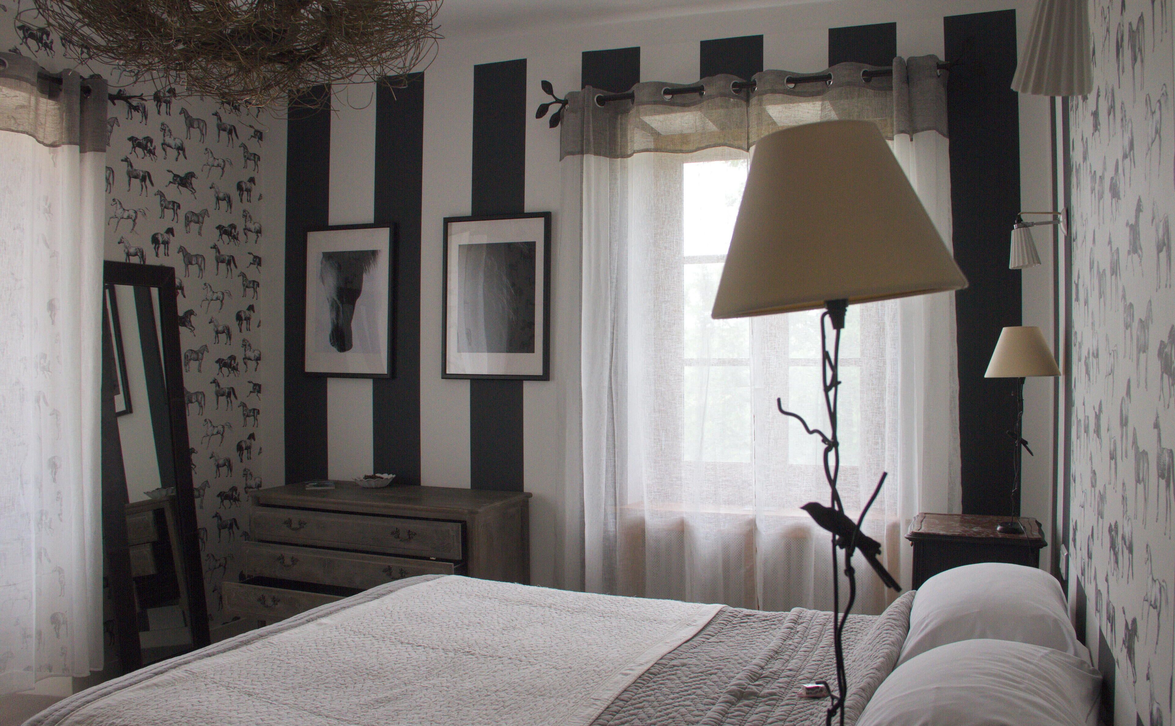 A bedroom with a bed, a dresser, a mirror, and a lamp.