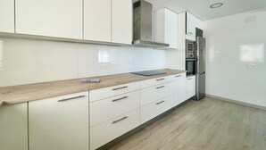 A modern kitchen with white cabinetry, a wooden countertop, and stainless steel appliances.