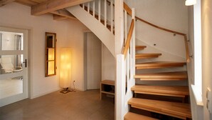 Una escalera con escalones de madera y barandillas blancas, que conduce a un piso superior.
