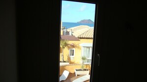 A view through a window of a room with a small patio area, including a white chair and a potted plant. - SEAHAUS FUERTE in a residential complex directly on the sea. (Corralejo)