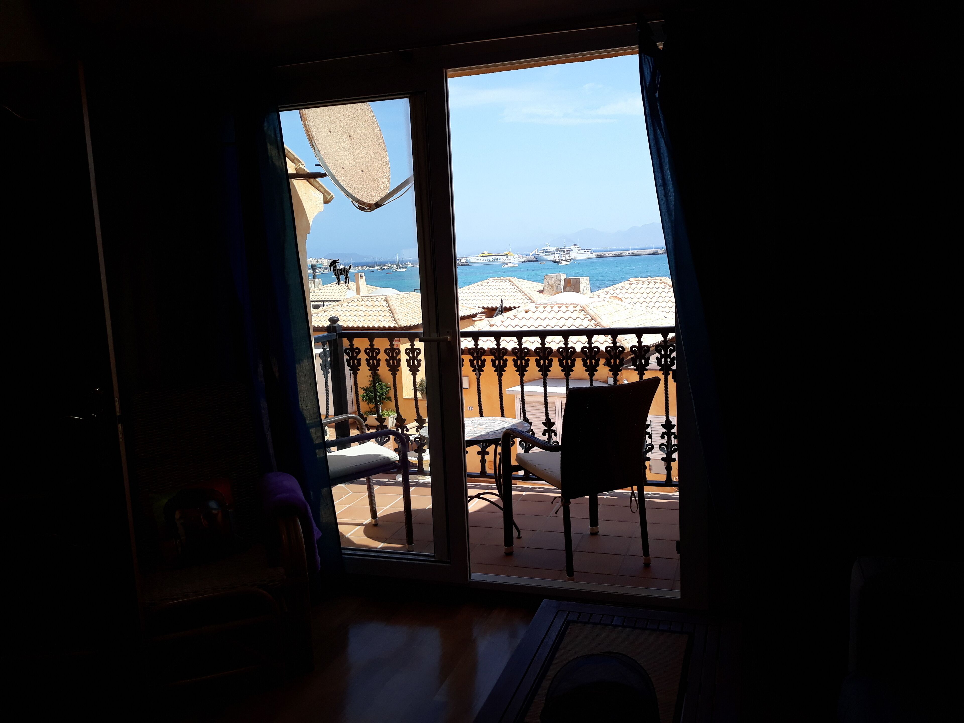 Une chambre avec vue sur la côte, comprenant un balcon avec une chaise et une table, ainsi qu’une porte donnant sur l’extérieur.