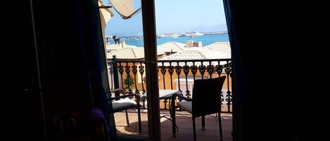 Une chambre avec vue sur la côte, comprenant un balcon avec une chaise et une table, ainsi qu’une porte donnant sur l’extérieur.