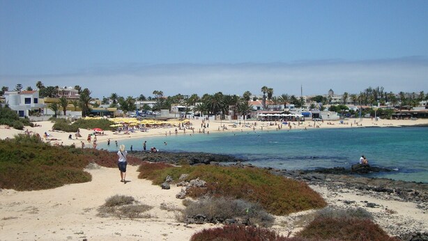 A beach with people, umbrellas, and buildings in the background. - SEAHAUS FUERTE in a residential complex directly on the sea. (Corralejo)