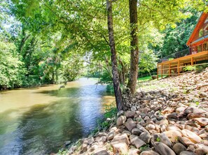 Un río con una pasarela de madera y rocas a la derecha.