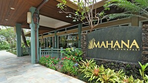Une enseigne pour « MAHANA à Ka'anapali », avec un mur de pierres et des plantes tropicales.