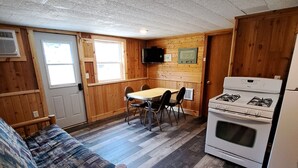 Une cuisine de taille réduite avec une table en bois, des chaises, une cuisinière et un réfrigérateur.