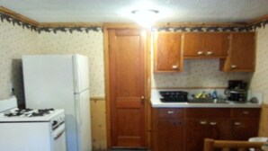 Une cuisine de taille réduite, équipée d’un réfrigérateur, d’une cuisinière et de meubles de rangement en bois.