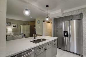 A modern kitchen with a stainless steel refrigerator, a marble countertop, and a pendant light. - Gorgeous townhouse with spectacular golf views in Palmetto Dunes! (Hilton Head Island)