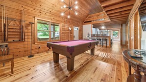 Un interior de madera con mesa de billar, paredes de madera y zona de comedor.